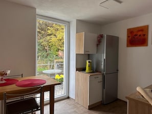 Eine kleine Küche mit Kühlschrank, einer Kaffeemaschine und einem Esstisch mit Stühlen.