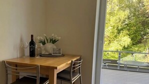 Ein Essbereich mit einem Holztisch, zwei Stühlen, einer Weinflasche und einer Blumenvase.