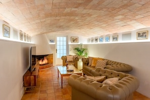 Ein Wohnzimmer mit Kamin, Ledersofa, Fernseher und gerahmten Bildern an der Wand.