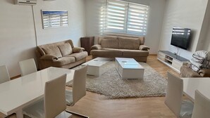 Una sala de estar moderna con un conjunto de sofá, una mesa de centro y un televisor.