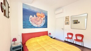 A bedroom with a bed, a painting, a mirror, and two chairs. - P092 – Porto Recanati, three-room apartment  (Porto Recanati)