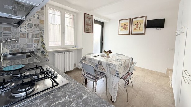 A compact kitchen with a gas stove, a sink, and a dining area with a table and chairs. - P092 – Porto Recanati, three-room apartment  (Porto Recanati)