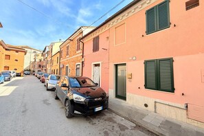 A street with parked cars and buildings with shutters.