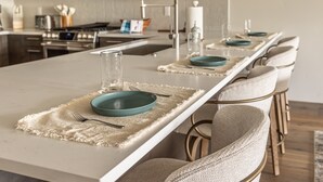 A modern kitchen with a long island, stainless steel appliances, and a white backsplash. - New Build Condo with Shared Hot Tub (Big Sky)