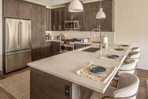A modern kitchen with stainless steel appliances, a central island, and bar seating. - Newly Listed, New Build Condo with Shared Hot Tub, Close to the Shuttle Stop (Big Sky)