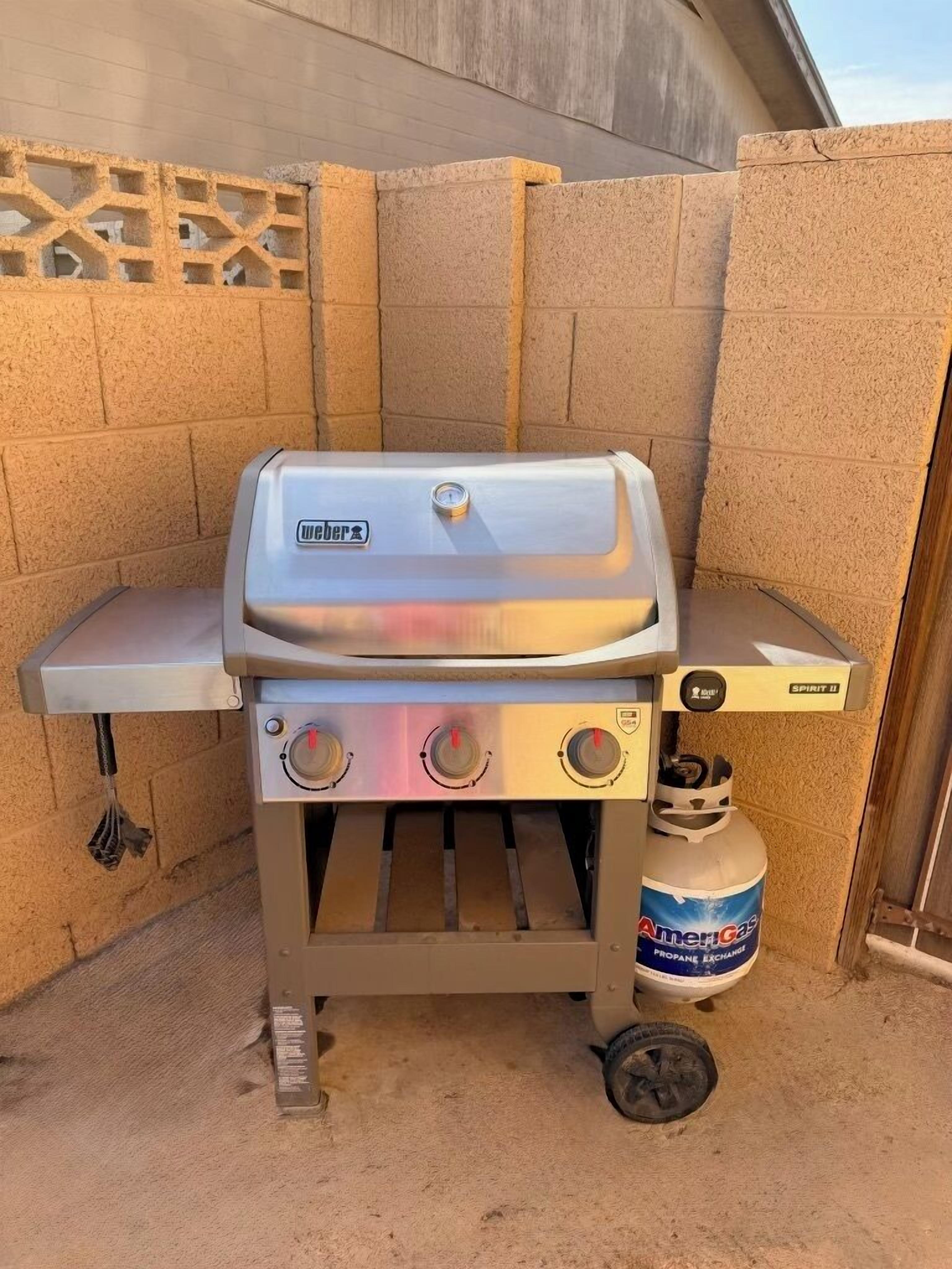 A Weber Spirit II portable gas grill with a propane tank.
