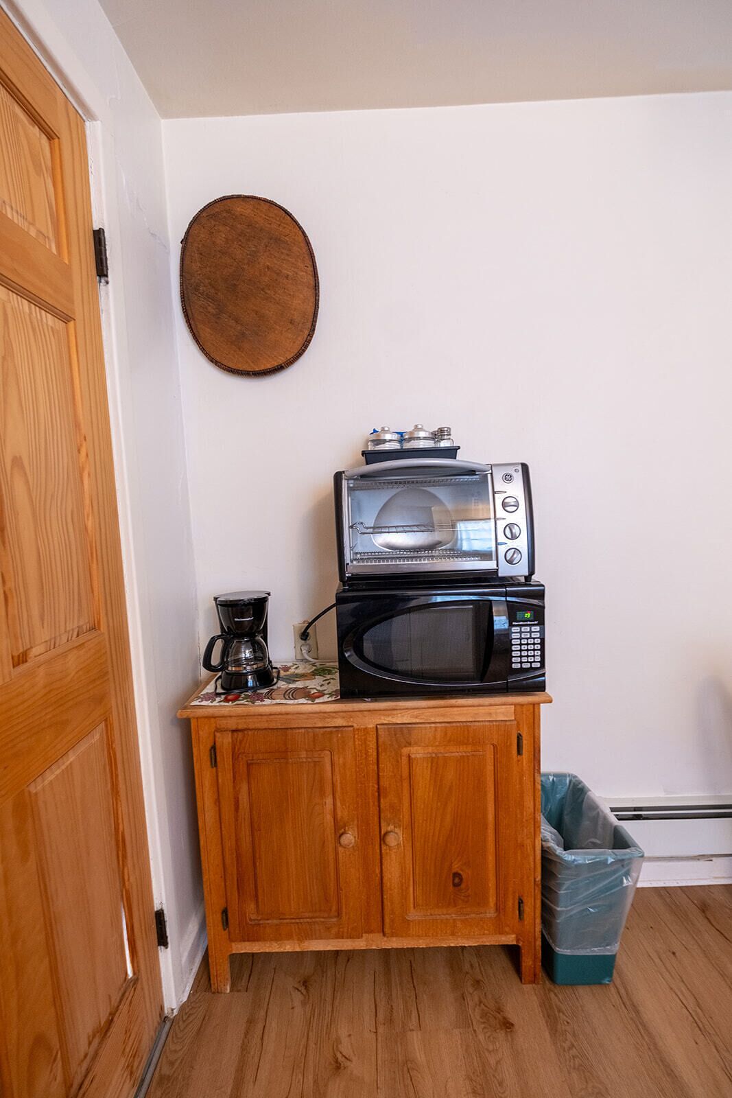 A kitchenette with a microwave, coffee maker, and a trash bin.