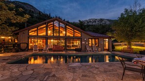 Una cabana de fusta amb piscina, grans finestres i zona d'estar a l'exterior.