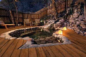 A wooden deck with a stone hot tub, surrounded by a wooden fence and a stone wall. - Wiesbaden Hot Springs Hotel & Spa (Ouray)
