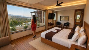 Habitación de hotel moderna con una cama grande, televisión, escritorio y vistas al exterior.