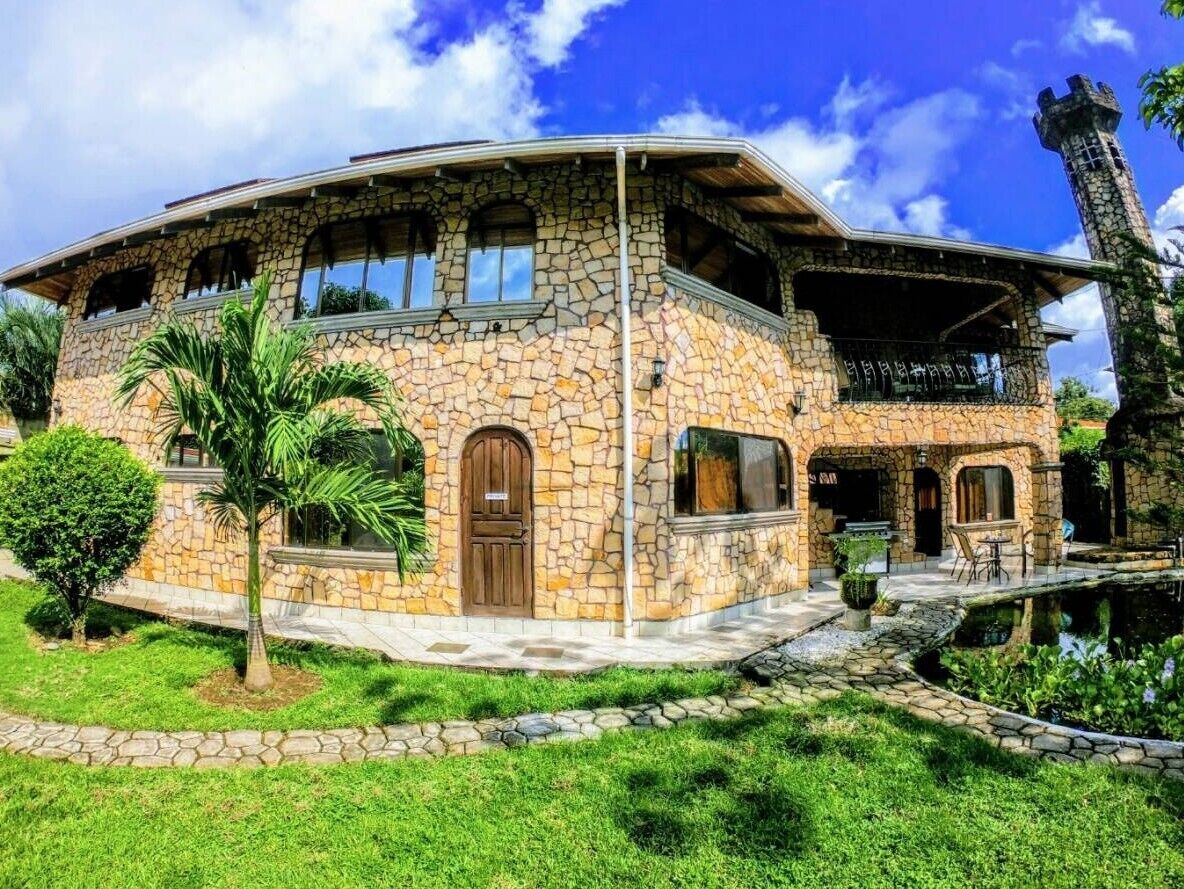 Une maison en pierre avec un toit incurvé, un balcon et un petit jardin.