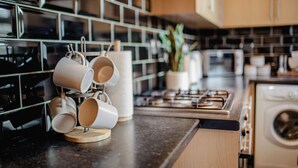 Une cuisine équipée d’une machine à café, d’un four à micro-ondes et d’une cuisinière.