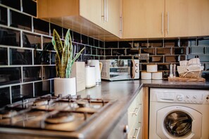 Una cocina equipada con estufa, microondas y lavadora.