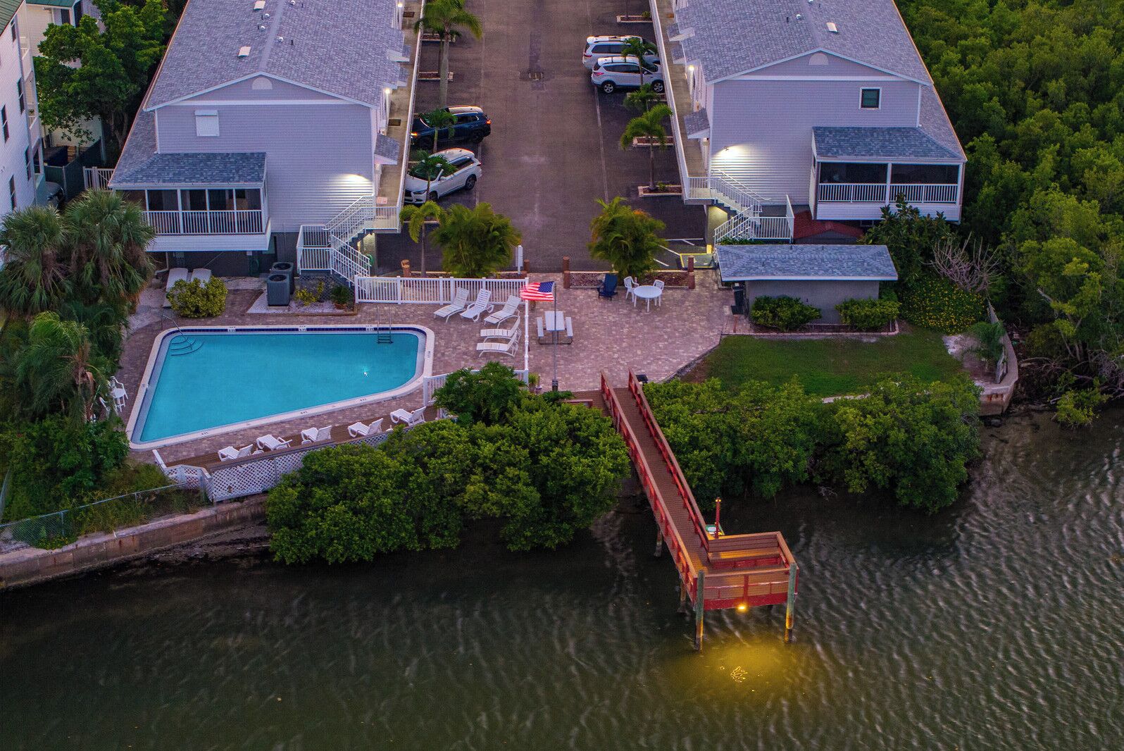 A residential area with a swimming pool, a dock, and a bridge over water.