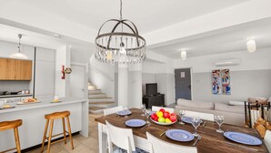 Una cocina moderna con zona de comedor, taburetes de madera, una araña y una escalera.