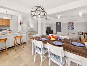 A modern kitchen with a dining area, wooden stools, a chandelier, and a staircase. - Villa Marilena: Spacious Protaras Villa with Pool (Protaras)