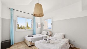 Un dormitorio con dos camas, una lámpara colgante y vistas al exterior.