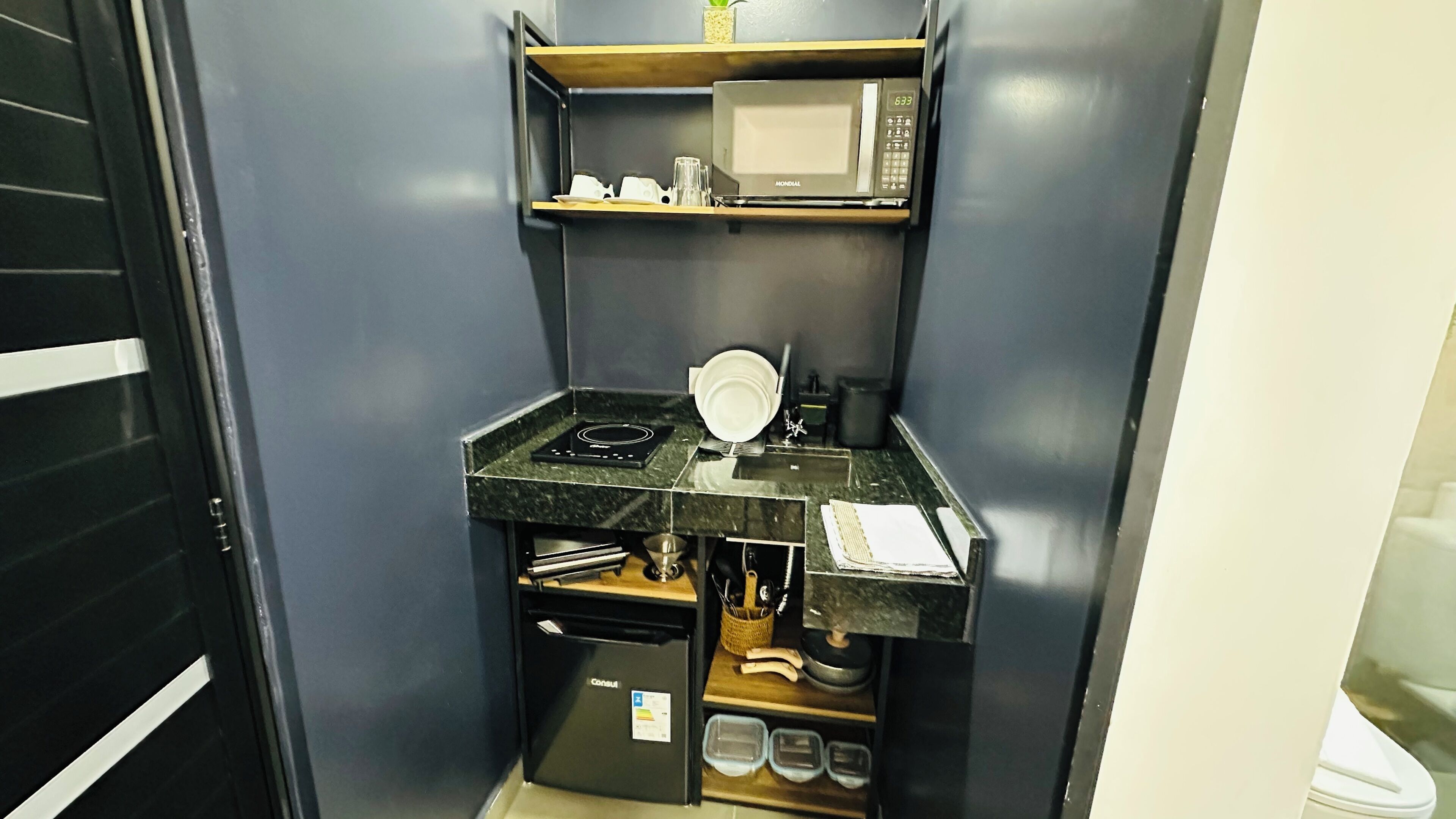 A compact kitchenette with a microwave, stove, and small refrigerator.