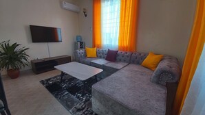 Una sala de estar con un sofá, una mesa de centro, un televisor y una planta en maceta.