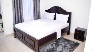 Un dormitorio con cama, mesita de noche y ventana con cortinas.