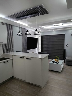 A modern kitchen with a central island, pendant lights, and a large dark door. - Gray House, Spacious and elegant apt., swimming pool, GYM (Punta Cana)