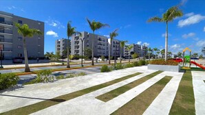 A modern urban area with multi-story buildings, a pedestrian crossing, and a playground. - Gray House, Spacious and elegant apt., swimming pool, GYM (Punta Cana)