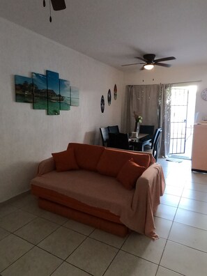 A living room with a sofa, a ceiling fan, a dining area with chairs, and artwork on the wall. - Casa Atardecer (Playa del Carmen) Los Olivos (Playa del Carmen)
