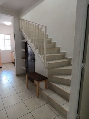 A staircase with a wooden bench at the bottom, leading to a landing with a door. - Casa Atardecer (Playa del Carmen) Los Olivos (Playa del Carmen)