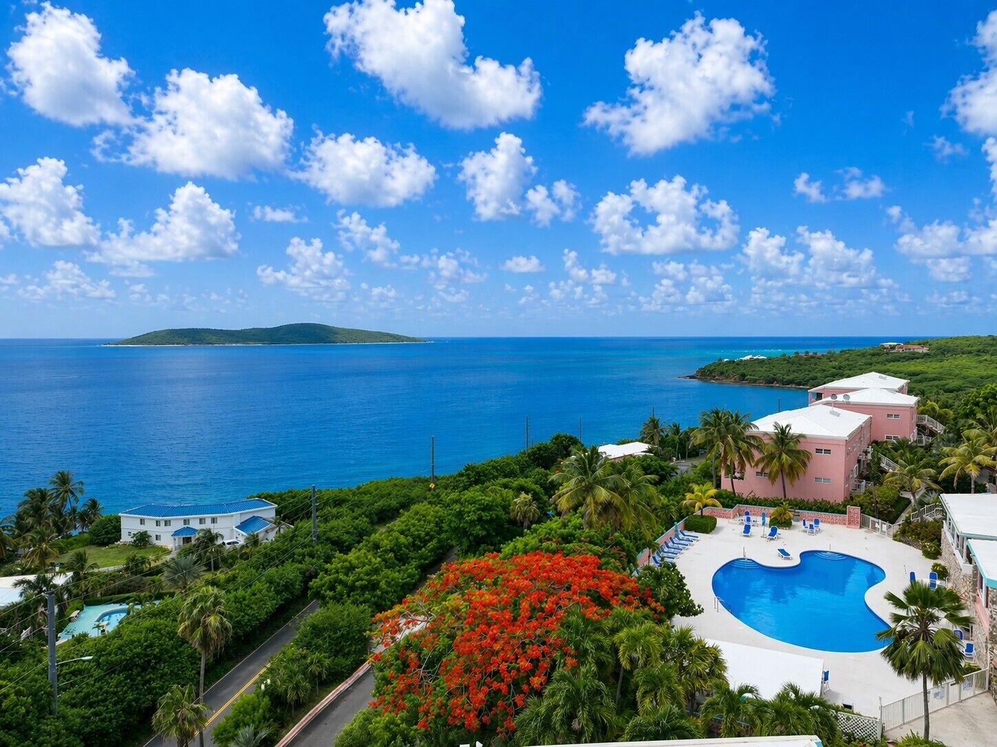 A resort with a swimming pool, lush greenery, and a view of the ocean.