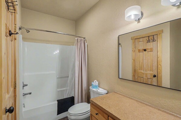A bathroom with a bathtub, toilet, and a mirror.