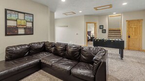 Ein Zimmer mit einer modularen Ledersofa, einem Kicker und einem Wandbild.