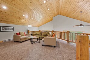 A spacious living room with a high wooden ceiling, a glass coffee table, two sofas, and a wooden railing overlooking a view. - Homestake Slopeside Chalet at Terry Peak (Lead)