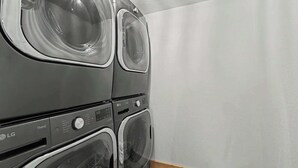 Eine gestapelte Waschmaschine und ein Trockner mit Bedienfeld und einer Glastür.