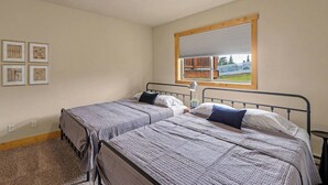 Ein Schlafzimmer mit zwei Betten, einem Fenster mit Jalousien und einer Deckenleuchte.