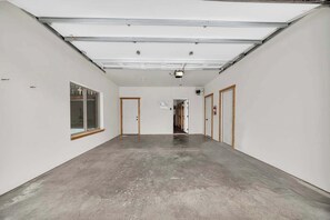 A hallway with white walls, a concrete floor, and doors on both sides. - Kussy Slopeside Chalet at Terry Peak (Lead)