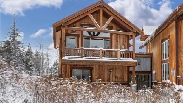 Eine Holzhütte mit Balkon, einem zweiten Stock und einem großen Fenster.