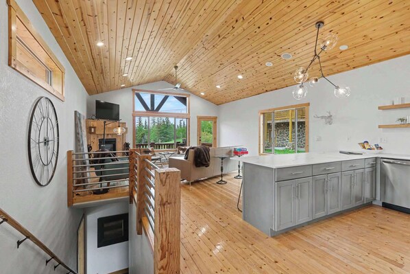 A spacious kitchen with a large island, wooden ceiling, and a view of the outdoors. - Kussy Slopeside Chalet at Terry Peak (Lead)