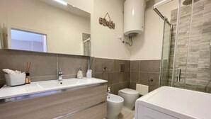 Een moderne badkamer met een wastafel met dubbele wastafel, een toilet, een douchecabine en een grote spiegel.