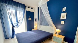 Een slaapkamer met een bed, nachtkastjes, een hemelbed en wanddecoraties.