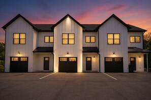 Ein mehrgeschossiges Wohnhaus mit mehreren Garagentoren und Außenbeleuchtung.