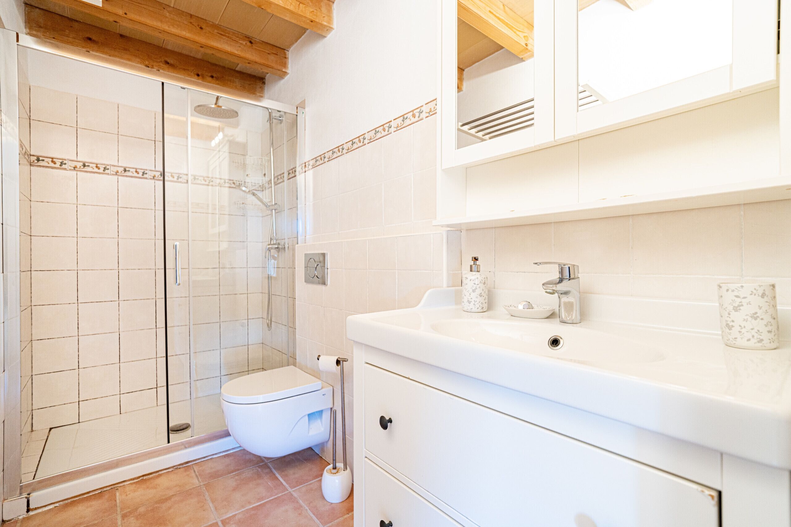 A bathroom with a shower, toilet, sink, and cabinets.