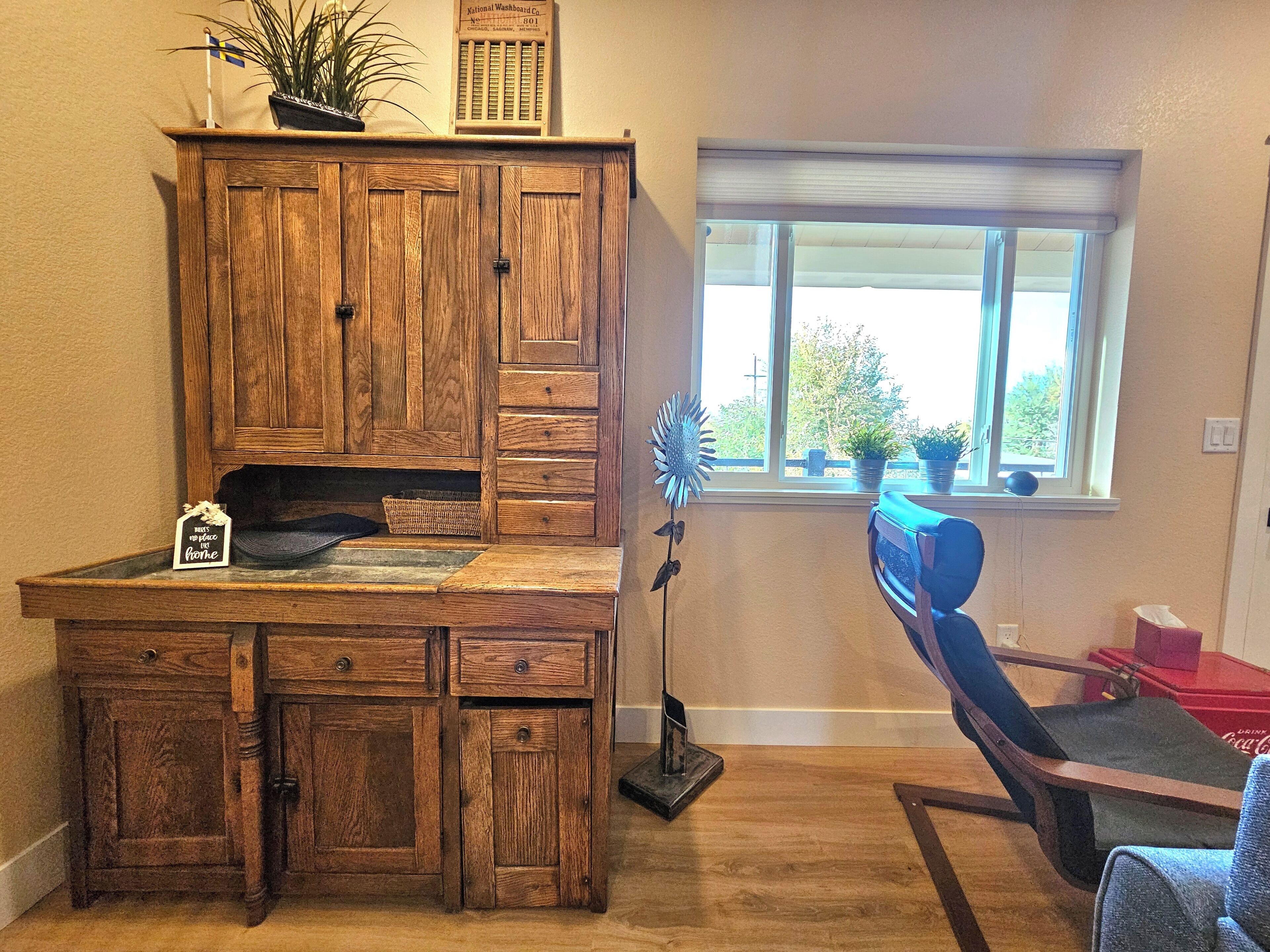 A wooden desk with drawers, a potted plant, a decorative item, and a window with a view of trees.