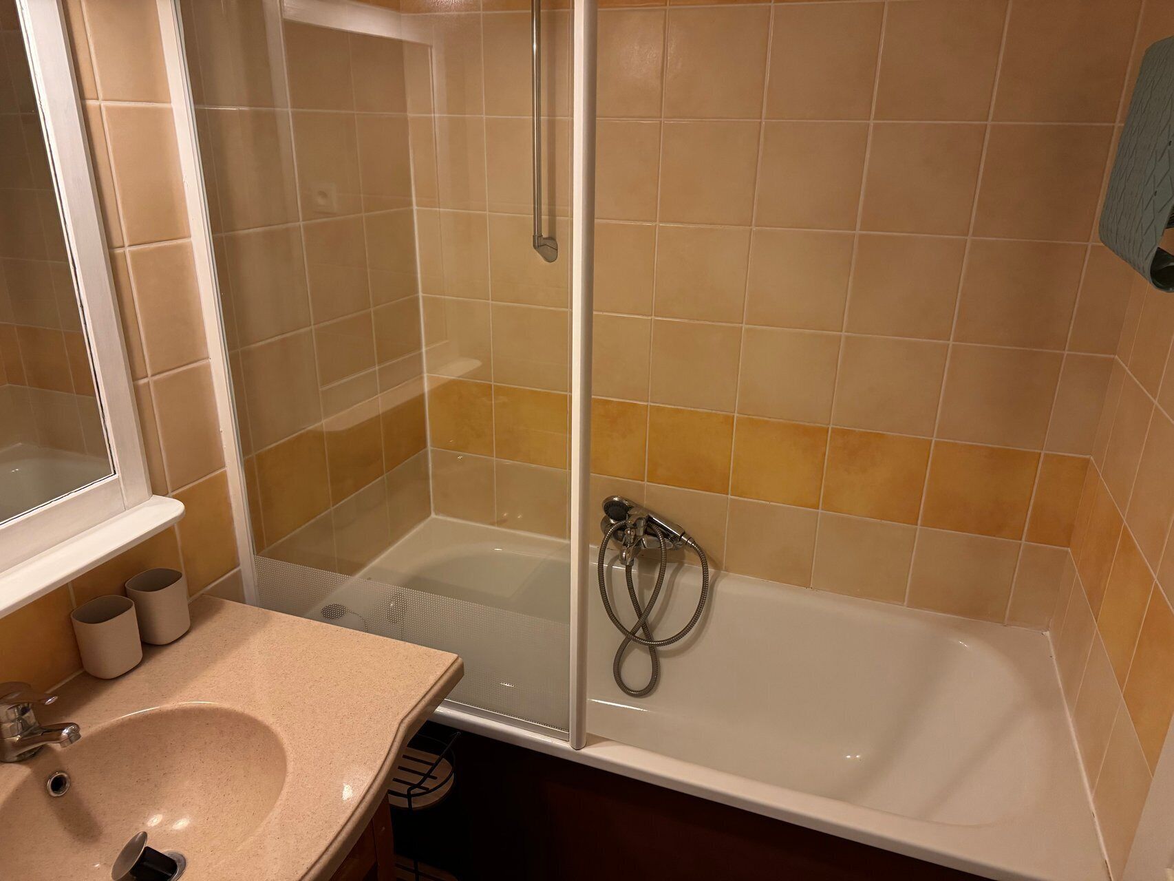 Un baño con lavamanos, espejo, ducha y paredes de azulejos.
