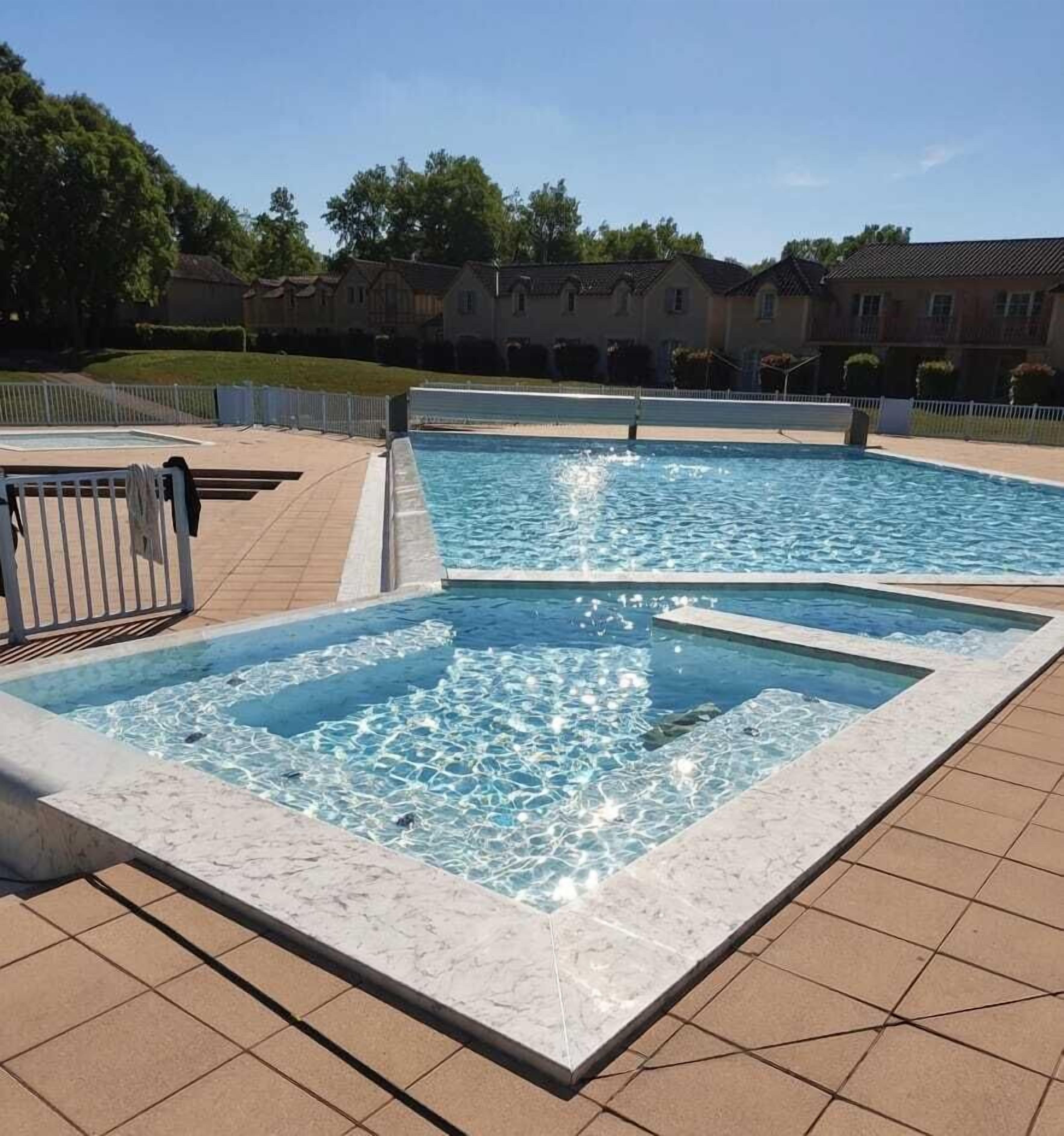 Une piscine rectangulaire à l’eau claire, entourée d’une terrasse carrelée.