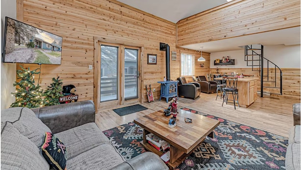 A log cabin interior with a living room, dining area, and a staircase.