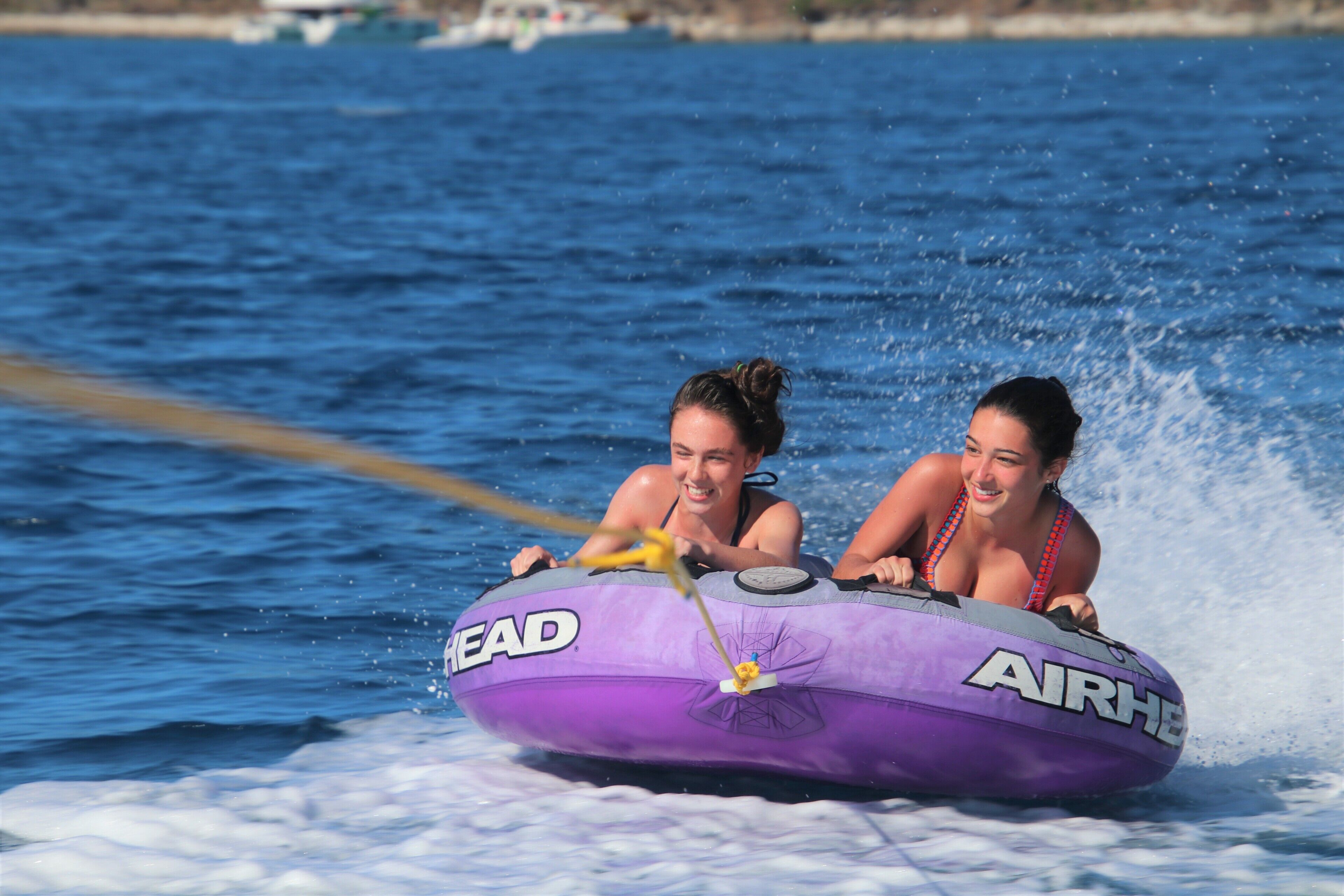 Duas pessoas em um barco inflável roxo, com as marcas 'HEAD' e 'AIRHE' visíveis.