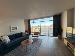 A modern living room with a sofa, armchair, coffee table, and a large TV. - Sleek 2 Bedroom Apt. Downtown Austin! (Austin)