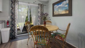 Un comedor con una mesa, sillas, un ventilador de techo y un cuadro de una playa.