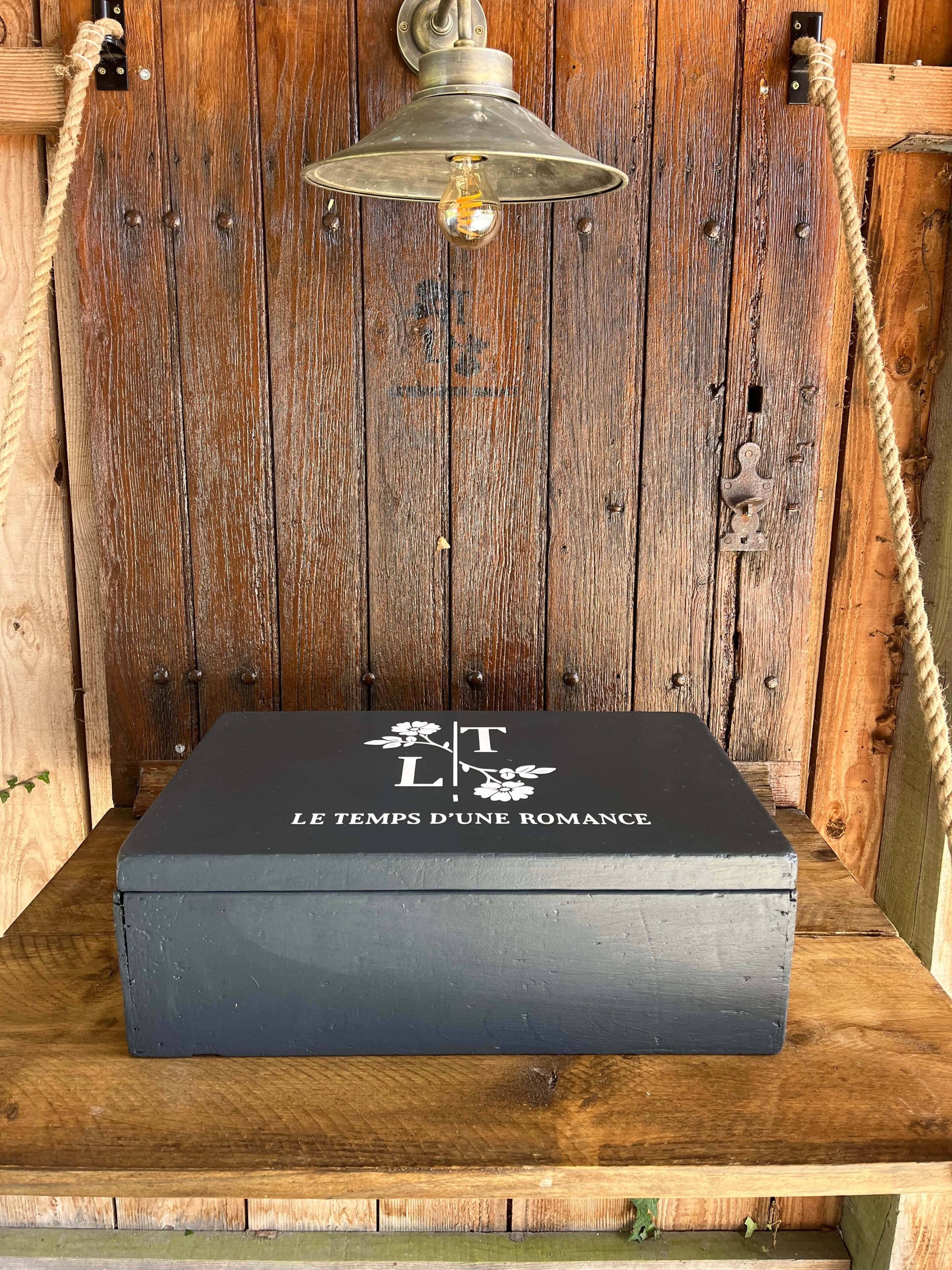 A rustic wooden wall with a metal light fixture and a black box with French text.