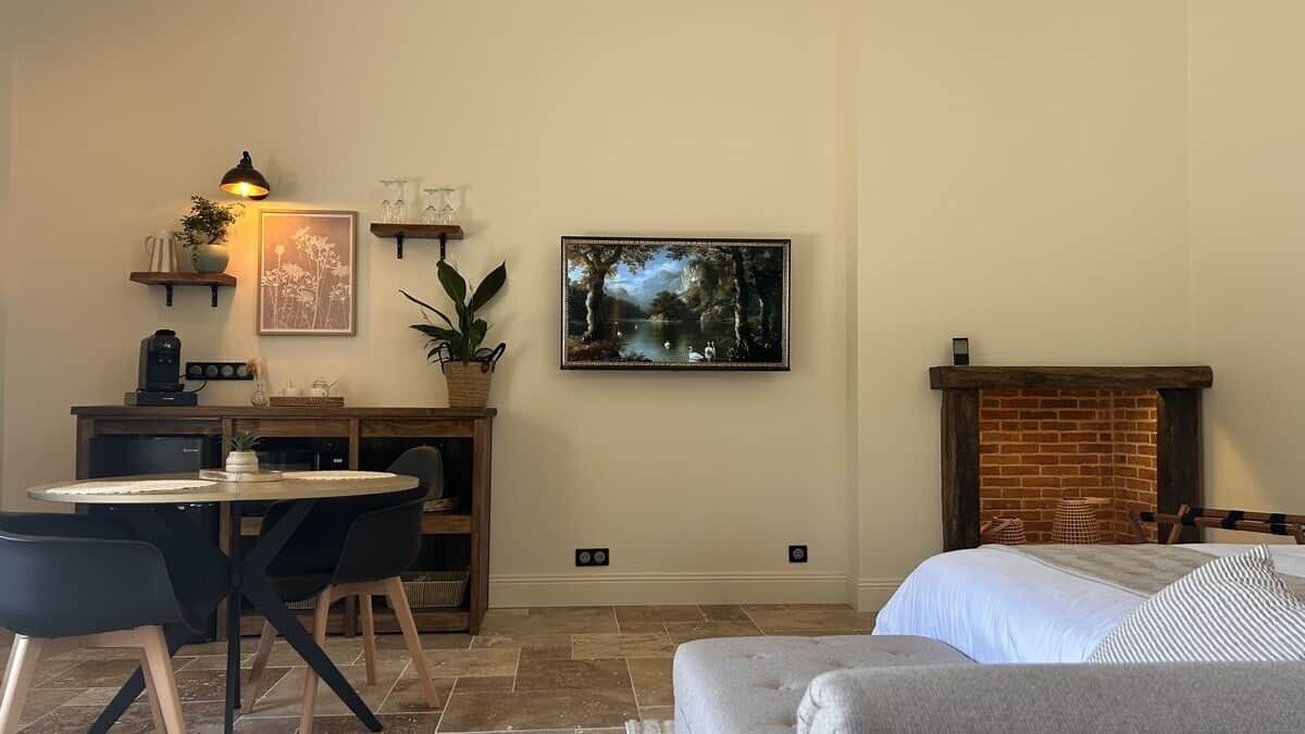 A cozy room with a fireplace, a dining table with chairs, a sofa, and artwork on the walls.